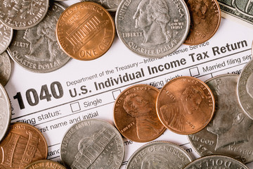 Closeup image of american 1040 Individual Income Tax return form with coins