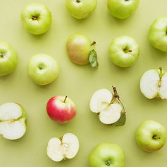 Red apple among green ones on green background flat layout top view. Fruits pattern. 