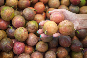 picking passion fruit in a store, female hand holds three tangerines