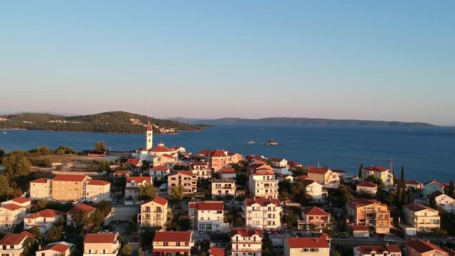 Seget Vranjica, Croatian Village. Aerial zoom in. Drone pull in at sunset in a typical town with Church of Croatina Martyrs over the city.  