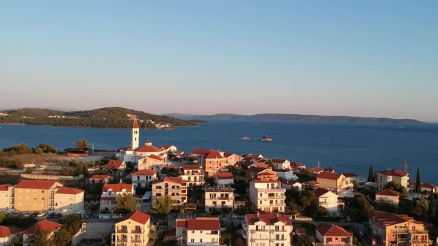 Aerial, Seget Vranjica, Croatian Village. Drone pull in at sunset in a typical town with Church of Croatina Martyrs over the city.  