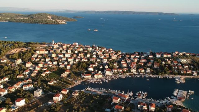 Seget Vranjica village and port. Aerial Tilt at sunrise with panoramic view of Croatian town with dock. 