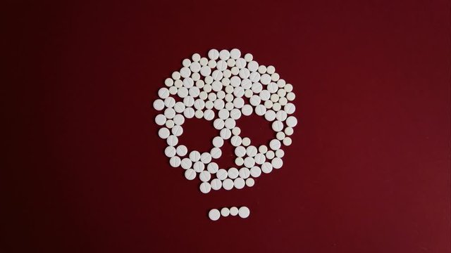 Image of a skull made of white pills. Motion animation. The movement of the lower jaw. Background in burgundy color.