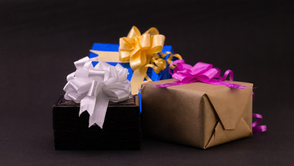 Close-up of colorful decorative gift box with bows and ribbons on black background