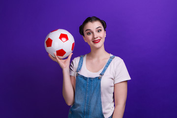 Portrait of smilling girl holding a soccer ball over isolated blue wall at studio