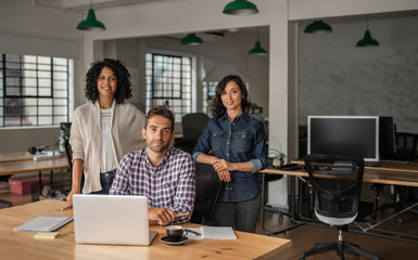 Smiling group of young designers working at an office desk