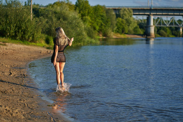 Fototapeta na wymiar teen girl on the beach on a sunset sunny day walks in a swimsuit and summer dress. copy space