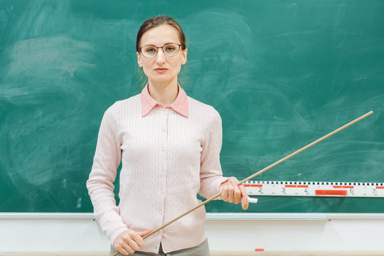 strict teacher standing in front of blackboard in class