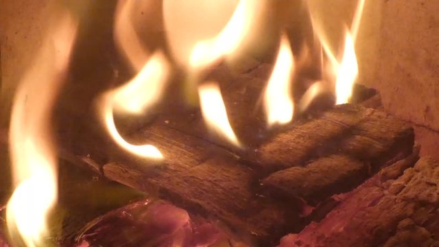 Burning firewood and coals ted with a poker. Closeup view of red hot glowing wood inside stove. Embers and fire in furnace or campfire. Abstract background.