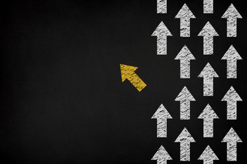 Yellow arrow coming out from the advancing white arrows on chalkboard, different business concept