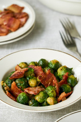Fried brussels sprouts with bacon in a white bowl