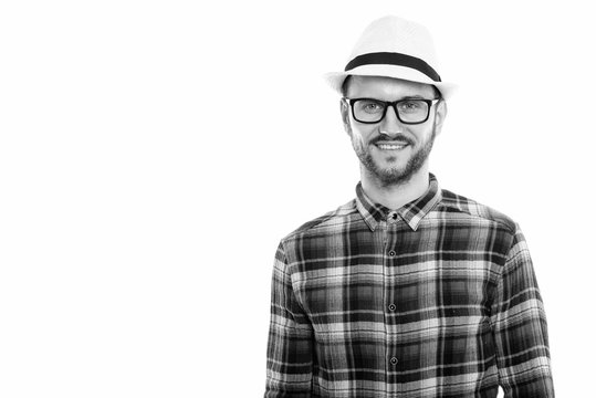 Studio shot of happy young man smiling while wearing hat and eyeglasses