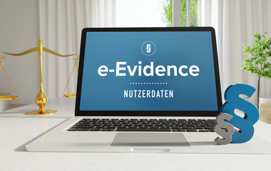 e-Evidence – Recht, Gesetz, Internet. Laptop im Büro mit Begriff auf dem Monitor. Paragraf und Waage. .