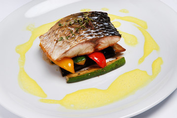 Grilled fish with vegetable on a gray background