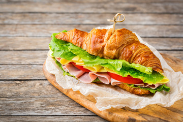 Fresh croissant sandwich with ham, cheese, lettuce and tomato