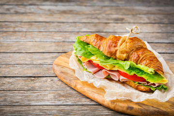 Fresh croissant sandwich with ham, cheese, lettuce and tomato