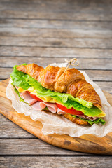 Fresh croissant sandwich with ham, cheese, lettuce and tomato