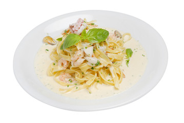 Fettuccine pasta with shrimp, tomatoes and herbs on a white isolated background