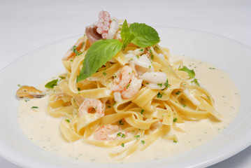 Fettuccine pasta with shrimp, tomatoes and herbs on a gray background