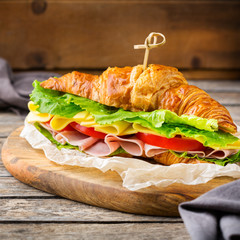 Fresh croissant sandwich with ham, cheese, lettuce and tomato