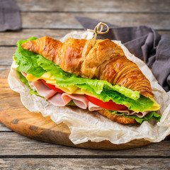 Fresh croissant sandwich with ham, cheese, lettuce and tomato