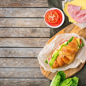 Fresh croissant sandwich with ham, cheese, lettuce and tomato