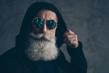 Close-up portrait of his he nice well-groomed attractive focused confident calm bearded gray-haired man wearing round blue violet specs life lifestyle isolated on concrete industrial wall background - Powered by Adobe