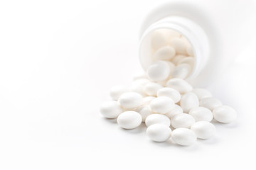 Fototapeta na wymiar Pill bottle spilling medical pills onto surface isolated on a white background.