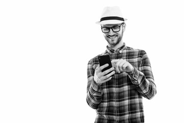 Studio shot of happy young man smiling while using mobile phone