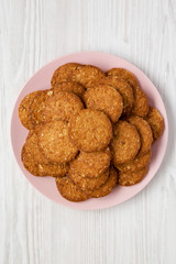 Cereal cookies on a pink plate on a white wooden background, top view. Flat lay, overhead, from above. Closeup.