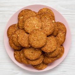 Cereal cookies on a pink plate on a white wooden surface, top view. Flat lay, overhead, from above. Close-up.