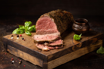 Juicy roast beef with spices sliced on a cutting Board, delicious meat, traditional food. On dark...