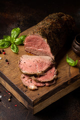 Juicy roast beef with spices sliced on a cutting Board, delicious meat, traditional food. On dark background