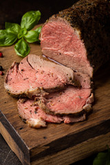 Juicy roast beef with spices sliced on a cutting Board, delicious meat, traditional food. On dark background