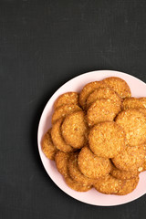 Cereal cookies on a pink plate on a black surface, top view. Flat lay, overhead, from above. Space for text.