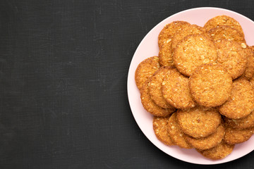 Top view, cereal cookies on a pink plate on a black surface. Flat lay, overhead, from above. Copy space.
