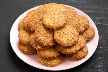 Cereal cookies on a pink plate on a black background, side view. Close-up.