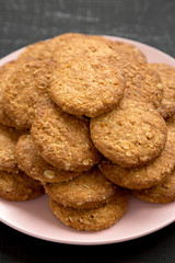 Cereal cookies on a pink plate on a black surface, side view. Close-up.