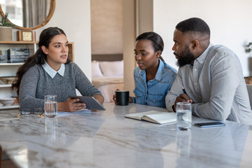 Financial advisor talking with an African American couple at home