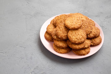Cereal cookies on a pink plate on a gray surface, side view. Copy space.