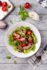 Salad with roast beef, tomato, onion, lettuce and mustard sauce on light background. Delicious healthy lunch with meat, diet food