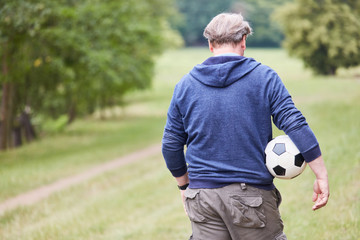 Naklejka premium Senior Mann mit einem Fußball unter dem Arm