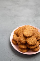 Cereal cookies on a pink plate on a gray background, low angle view. Copy space.