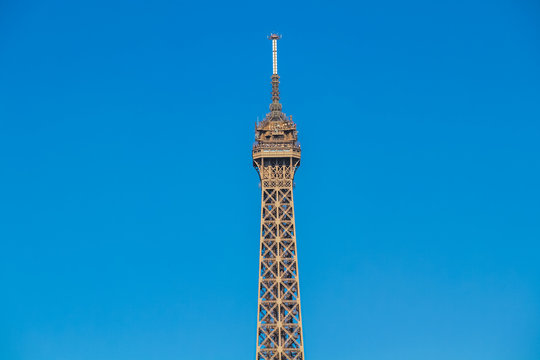 Close-up of the Eiffel Tower in Paris France  with elevators going up and down on a beautiful summer day with blue sky and white clouds