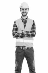 Studio shot of happy young man construction worker smiling and standing with arms crossed