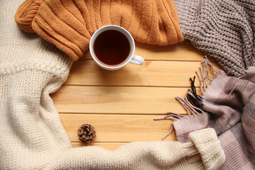 Fototapeta na wymiar cup of hot fragrant tea on a wooden background, autumn leaves, apple, cozy scarves and knitted sweaters, flat, concept hugge, winter or autumn mood, copy space