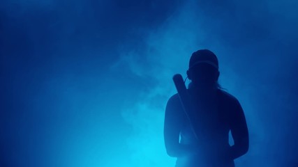 silhouette of ballplayer swinging bat during playing baseball. woman playing baseball on dark background with blue smoke. - Powered by Adobe