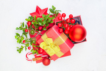 Merry Christmas concept. Red gift box with green holly branch, sweets and New Year decoration