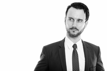 Studio shot of young businessman thinking while looking at distance