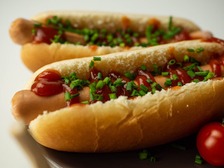 Hot dog z drobiową parówką, szczypiorkiem i ketchupem. Zbliżenie.